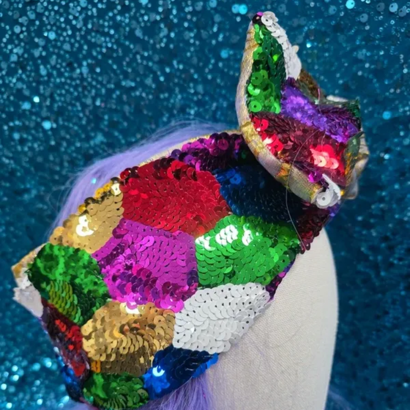 Mannequinhoofd met een kleurrijke paillettenstrik en een zilverkleurige, met goud geborduurde strik op een blauwe glitterachtergrond.