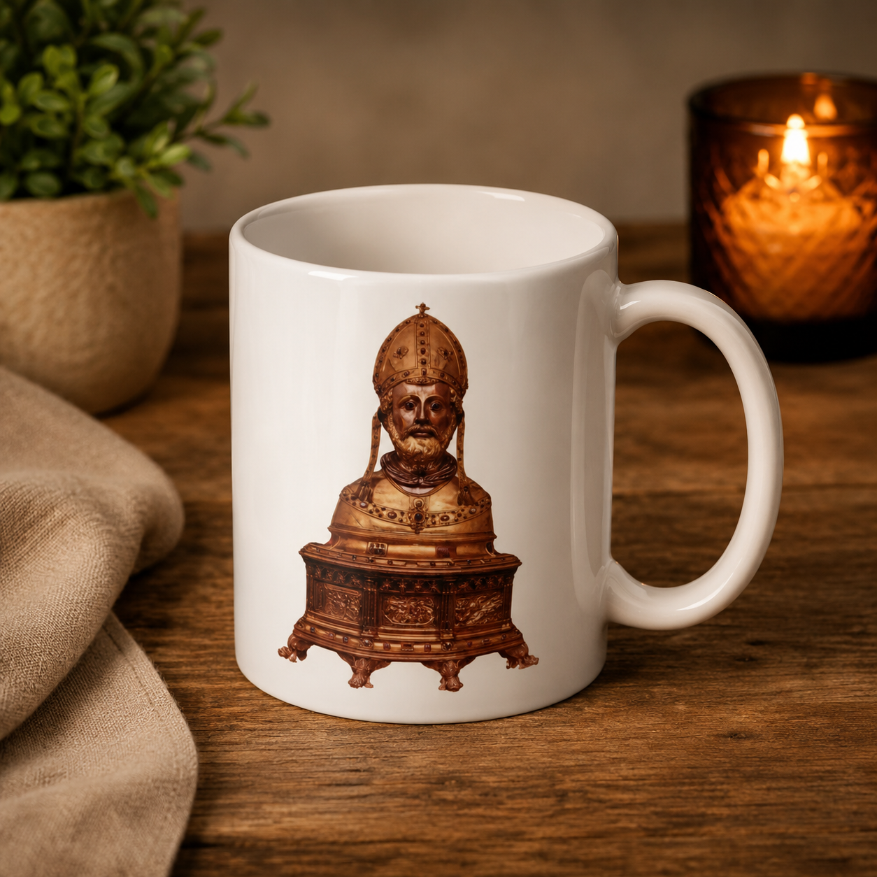 Witte mok met een bronzen buste-illustratie op een houten tafel, naast een kaars en een potplant.