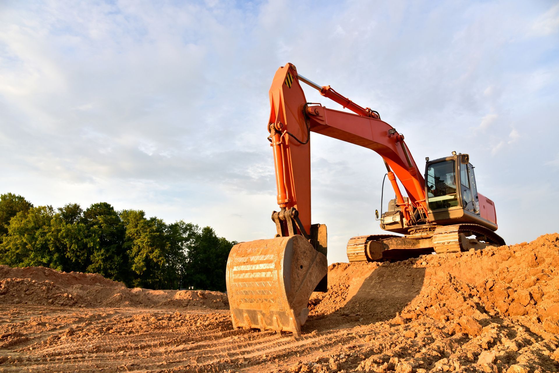 A large orange excavator is sitting on top of a pile of dirt.