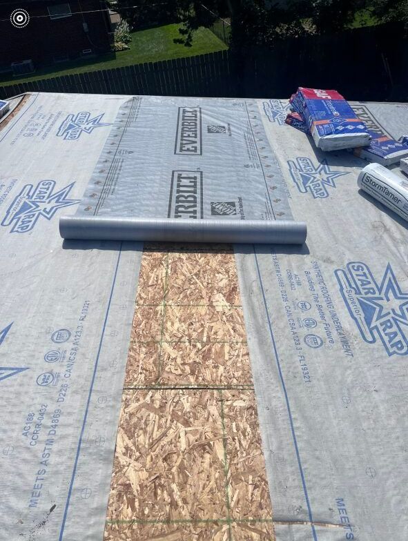 A roll of roofing material is being rolled up on a roof.