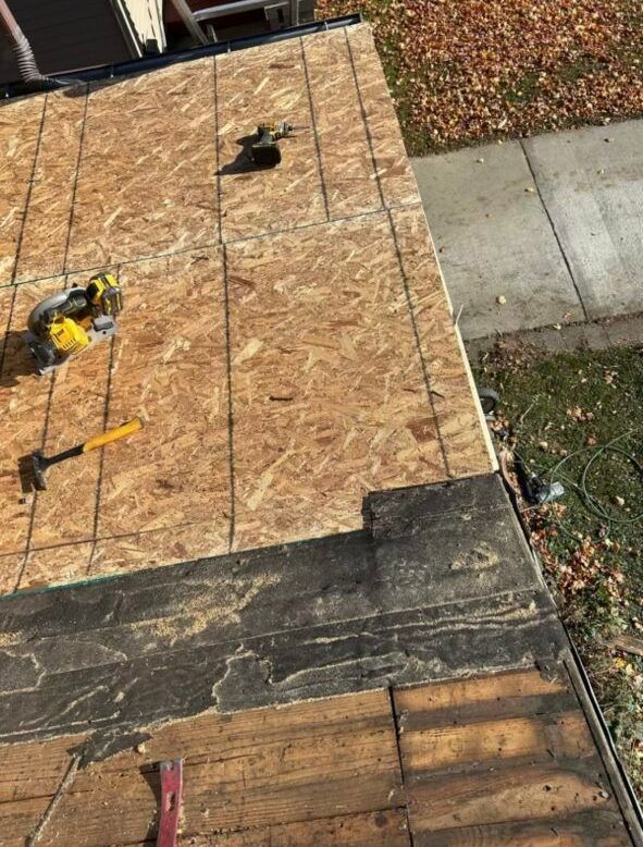 A person is working on a roof with a hammer and a saw.