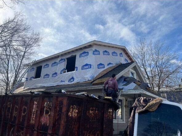 A man is working on the roof of a house.