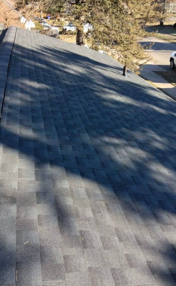 A roof with a lot of shingles on it and trees in the background.