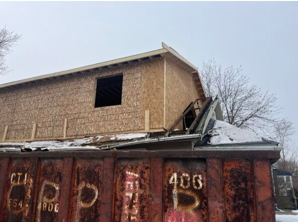 A house is being built on top of a rusty dumpster.