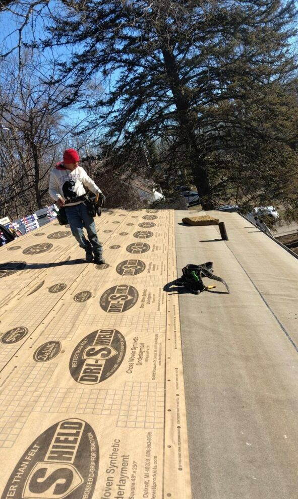 A man is standing on top of a roof with a piece of paper on it.