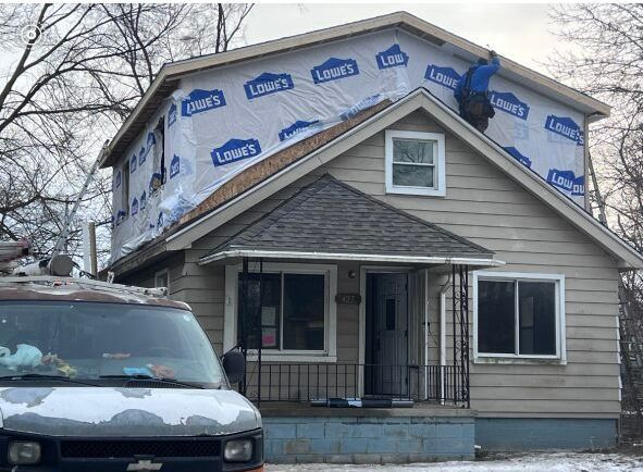 A white van is parked in front of a house that is being remodeled.