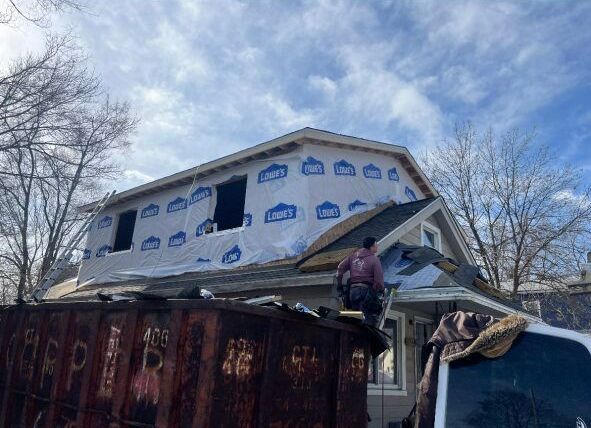A man is working on the roof of a house.
