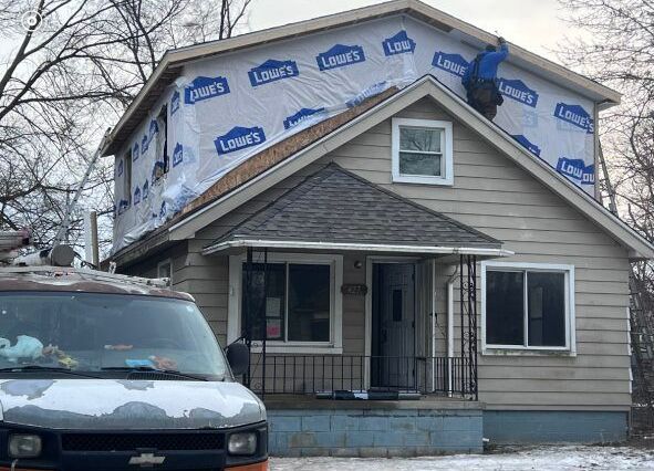 A van is parked in front of a house that is being remodeled.