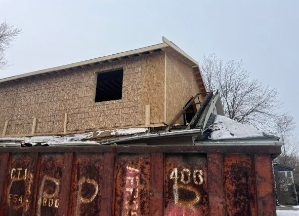 A house is being built on top of a rusty dumpster.