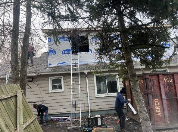 A couple of men are working on the roof of a house.