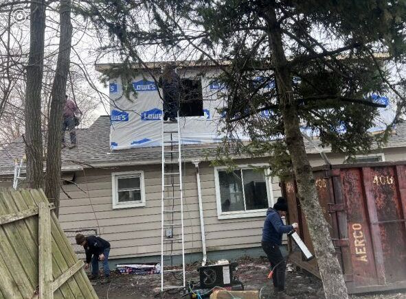 A group of people are working on the roof of a house.