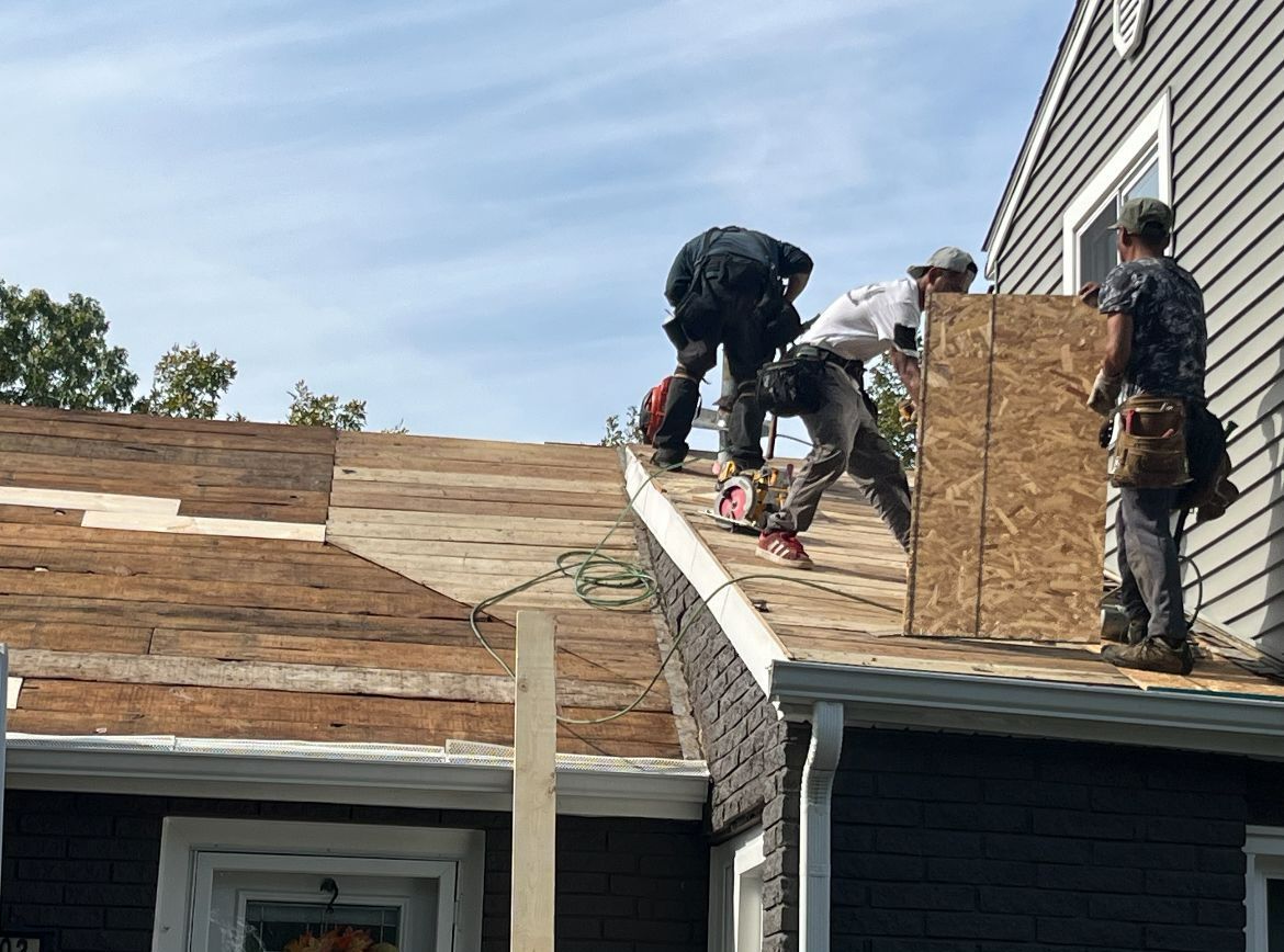 A group of men are working on the roof of a house.