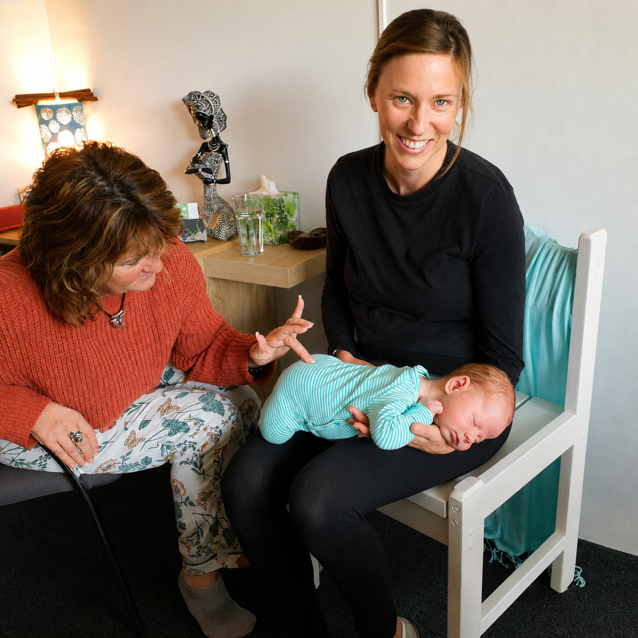 Two women with a sleeping baby on one’s lap in a cozy room