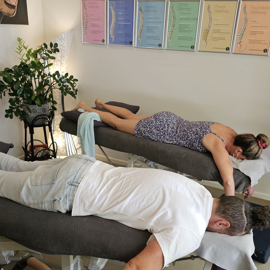 Massage therapist working on a person lying face down on a treatment table in a clinic room
