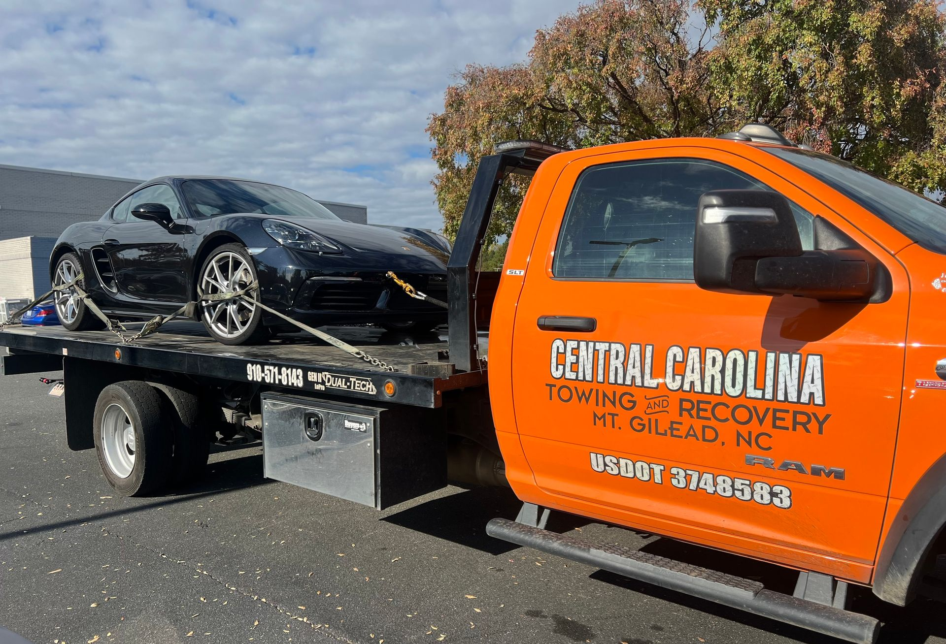 Black Porsche being towed by an orange Central Carolina Towing truck in Siler City, NC.
