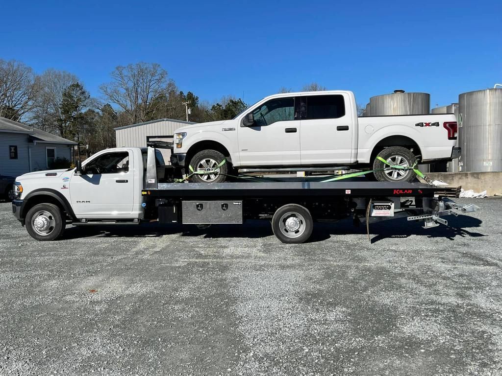 A white truck is being towed by a tow truck.