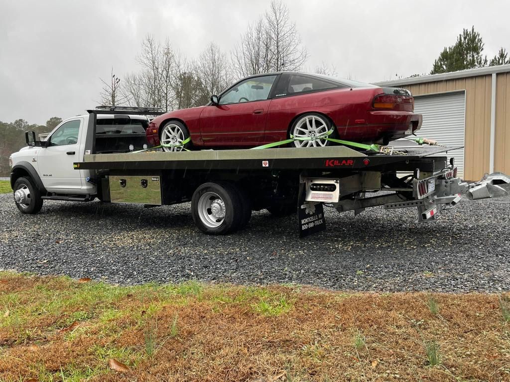 A red car is being towed by a tow truck.