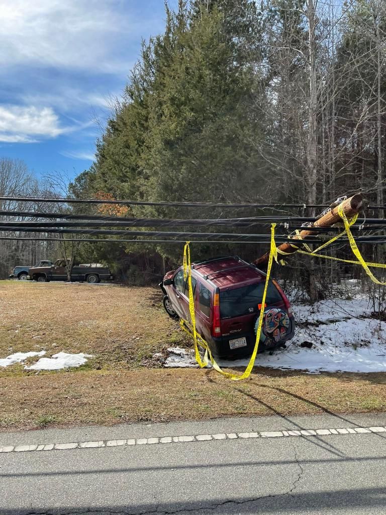 A red van is sitting under a power line on the side of the road.