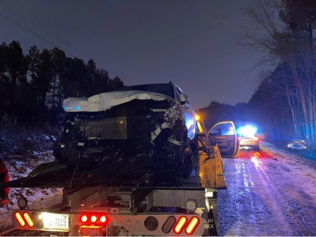 A car is being towed by a tow truck on a snowy road.