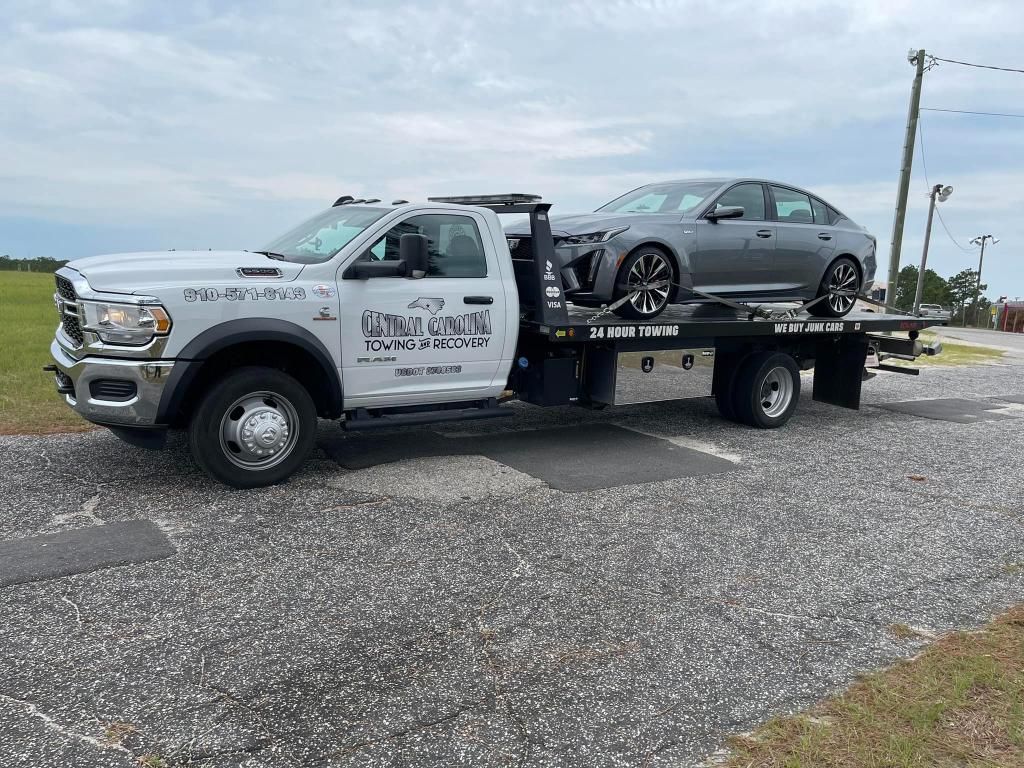 A tow truck is towing a car on the back of it.