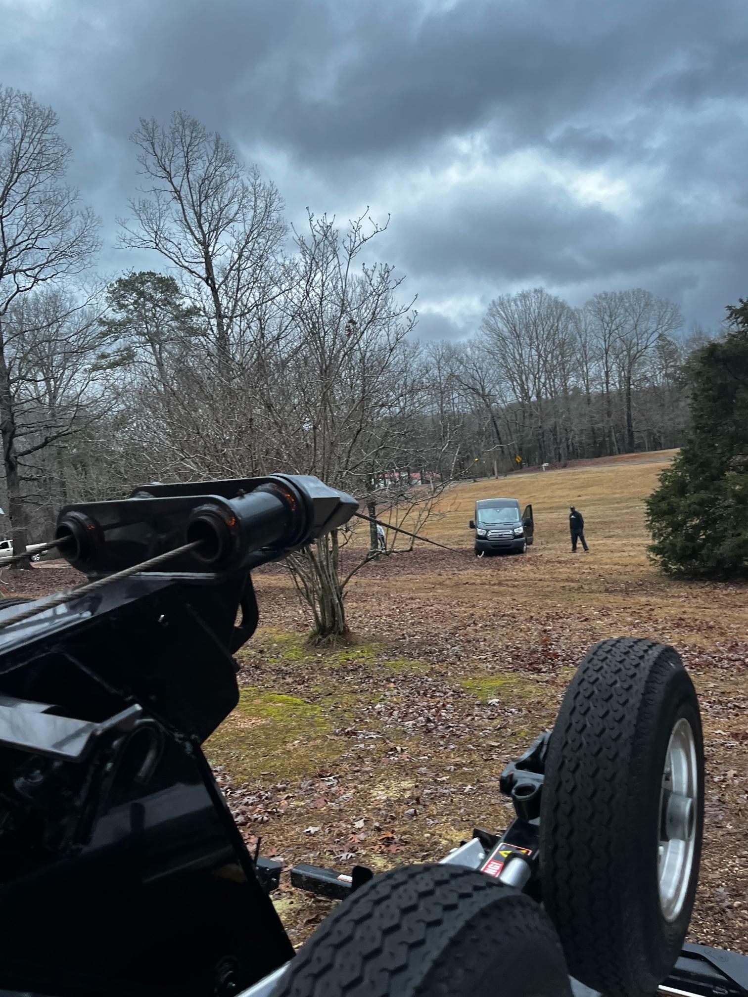 A tow truck is parked in a field with trees in the background.
