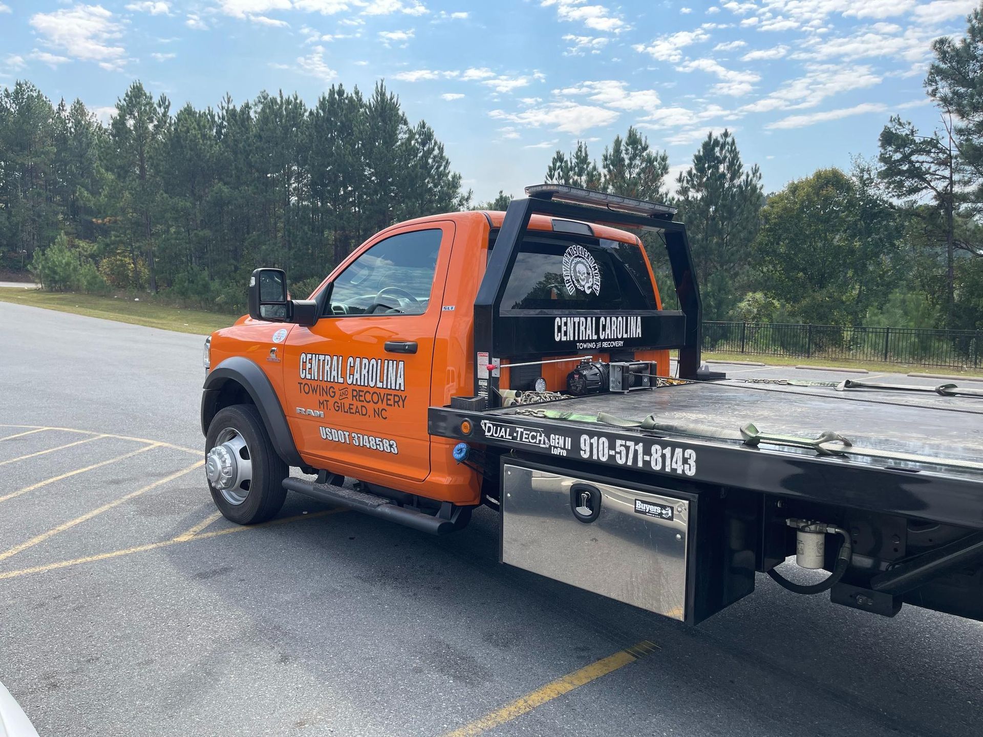 An orange tow truck is parked in a parking lot.