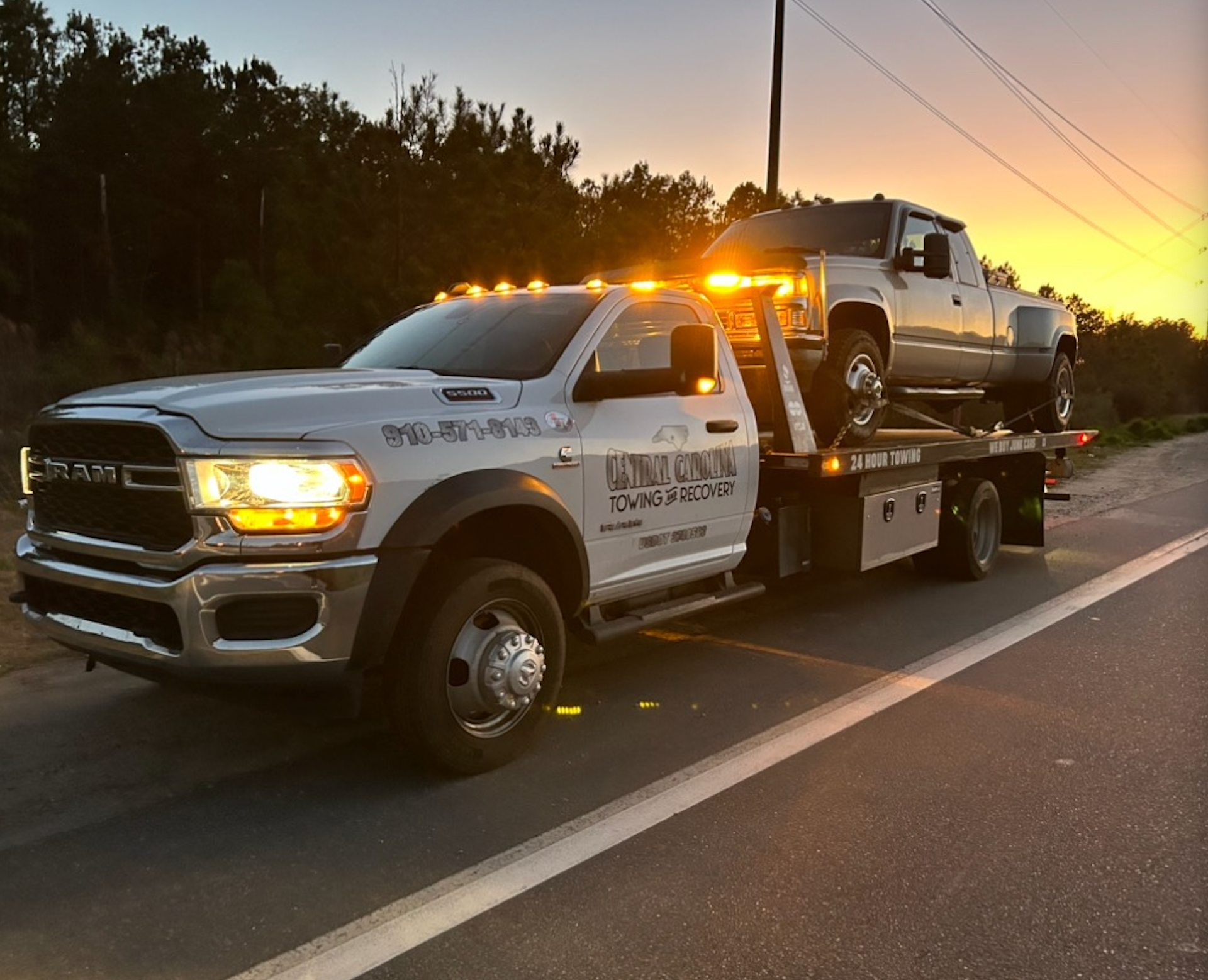 A tow truck is towing a truck on the side of the road.