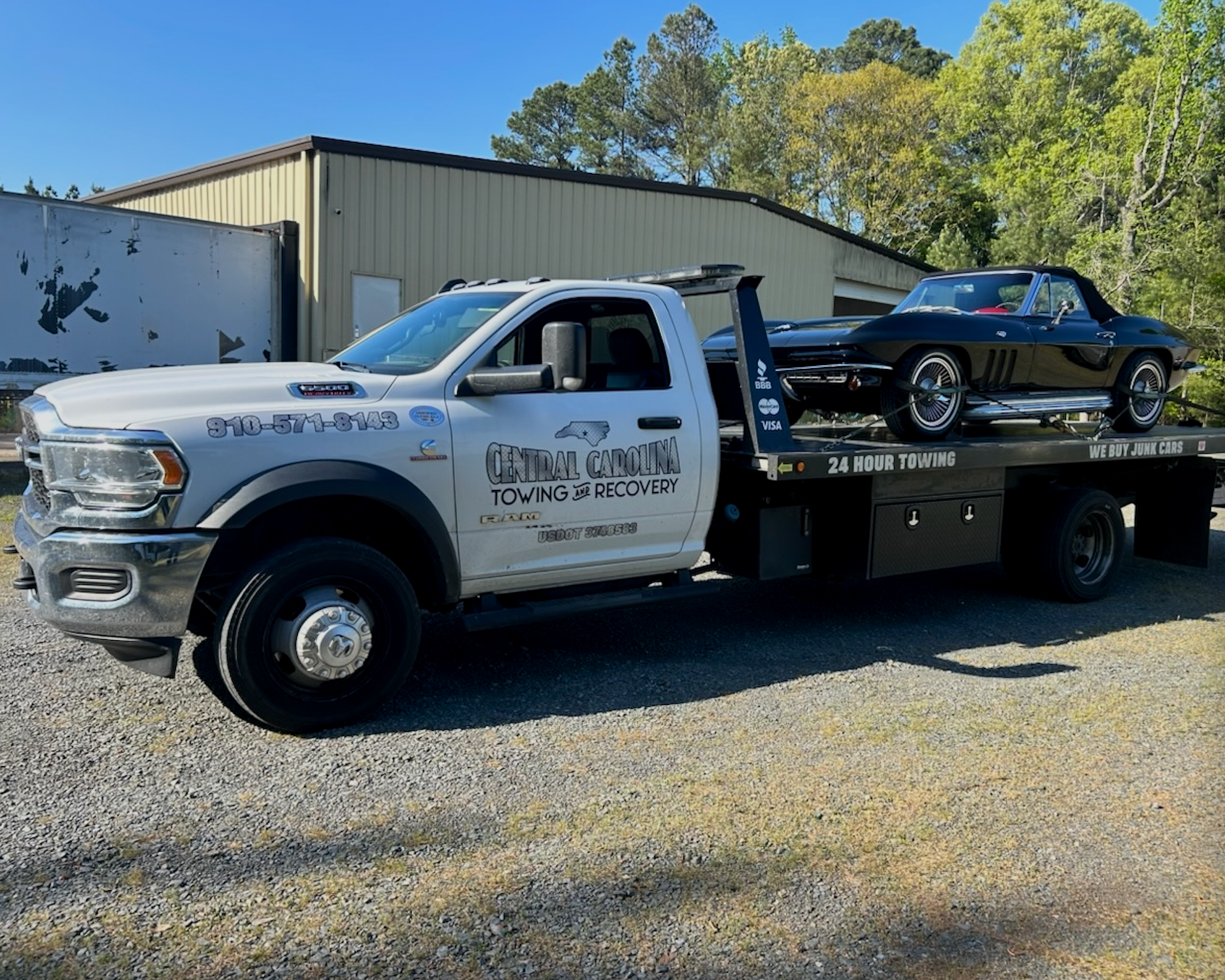 A white tow truck with a corvette on the back of it