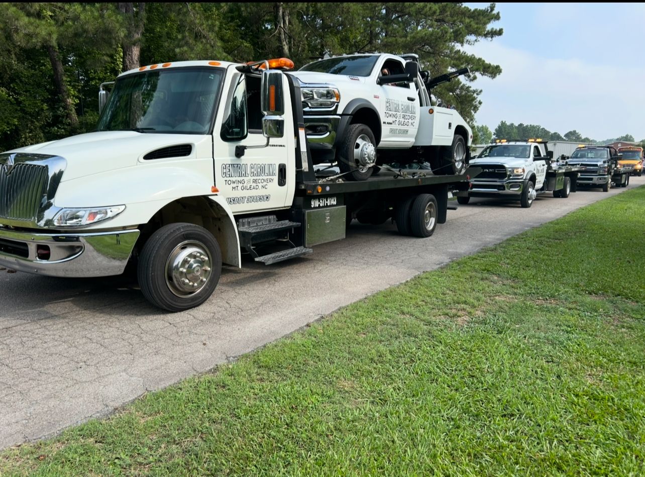 A tow truck is carrying a truck on the back of it.