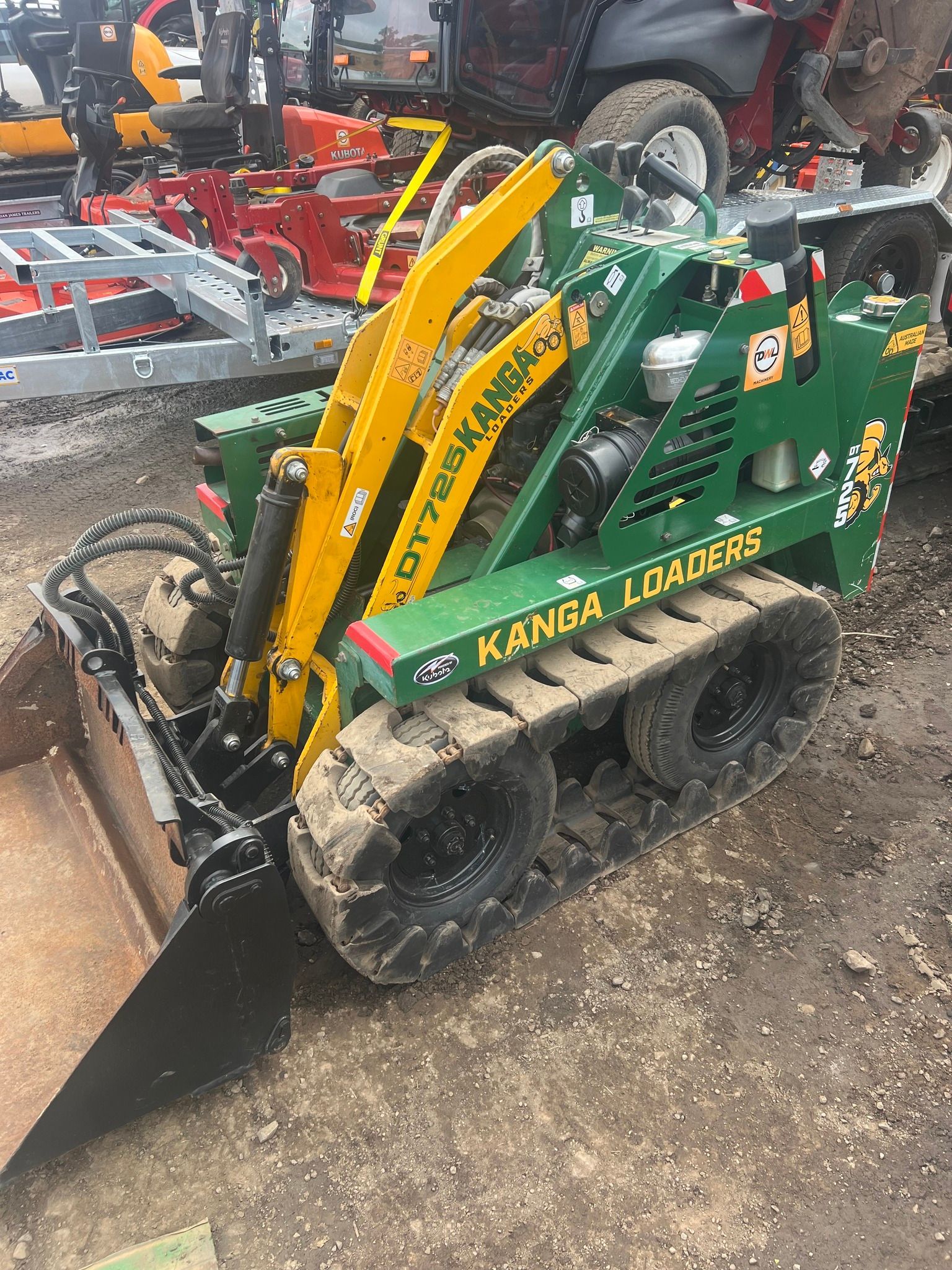 A green and yellow tractor is sitting on top of a dirt field.