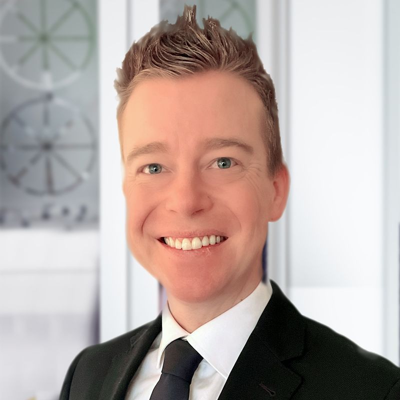 A man in a suit and tie is smiling for the camera