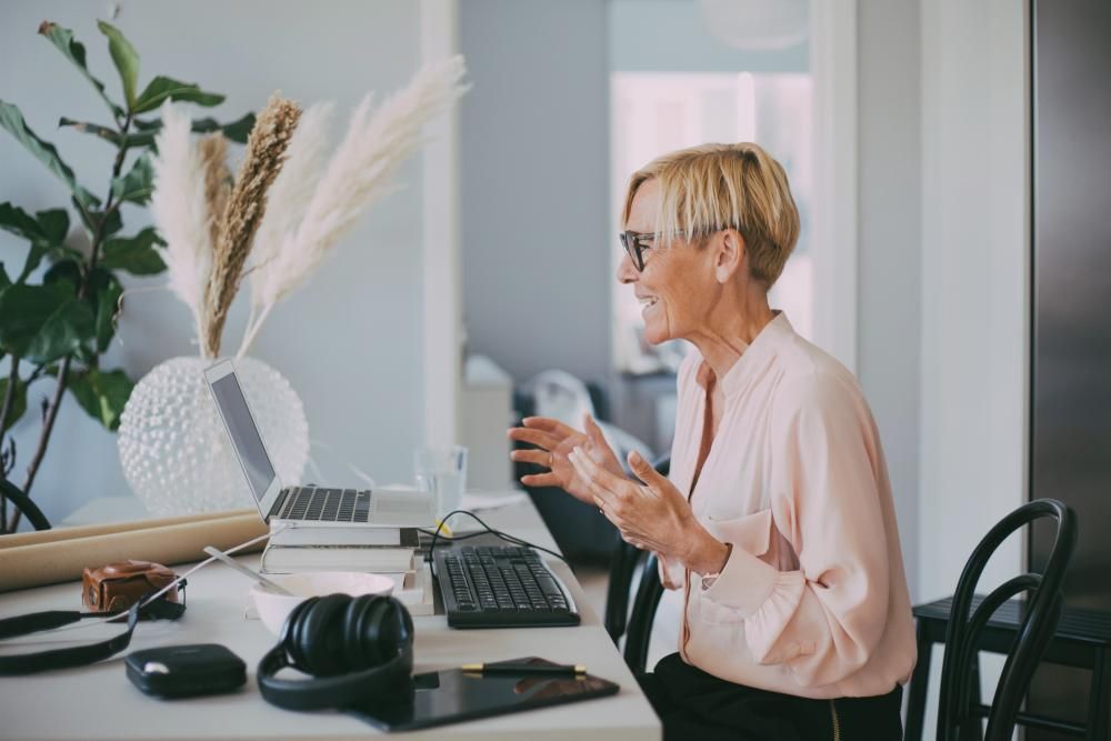 A woman is sitting at a desk in front of a laptop computer.