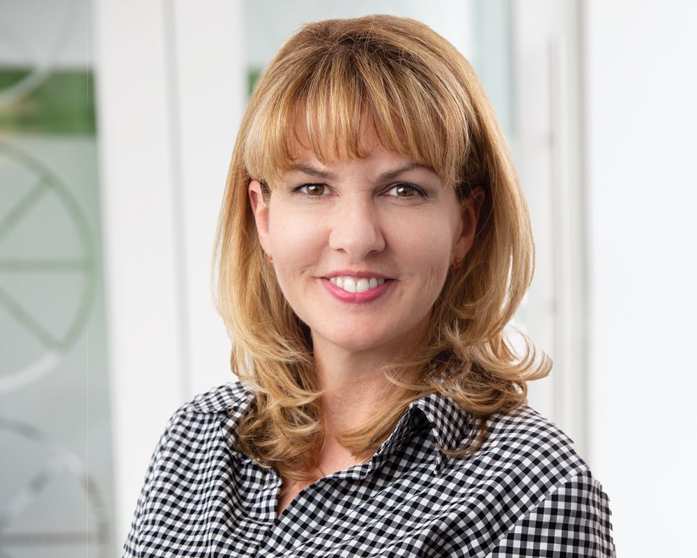 Mary Lou Martinez in a black and white checkered shirt is smiling for the camera.