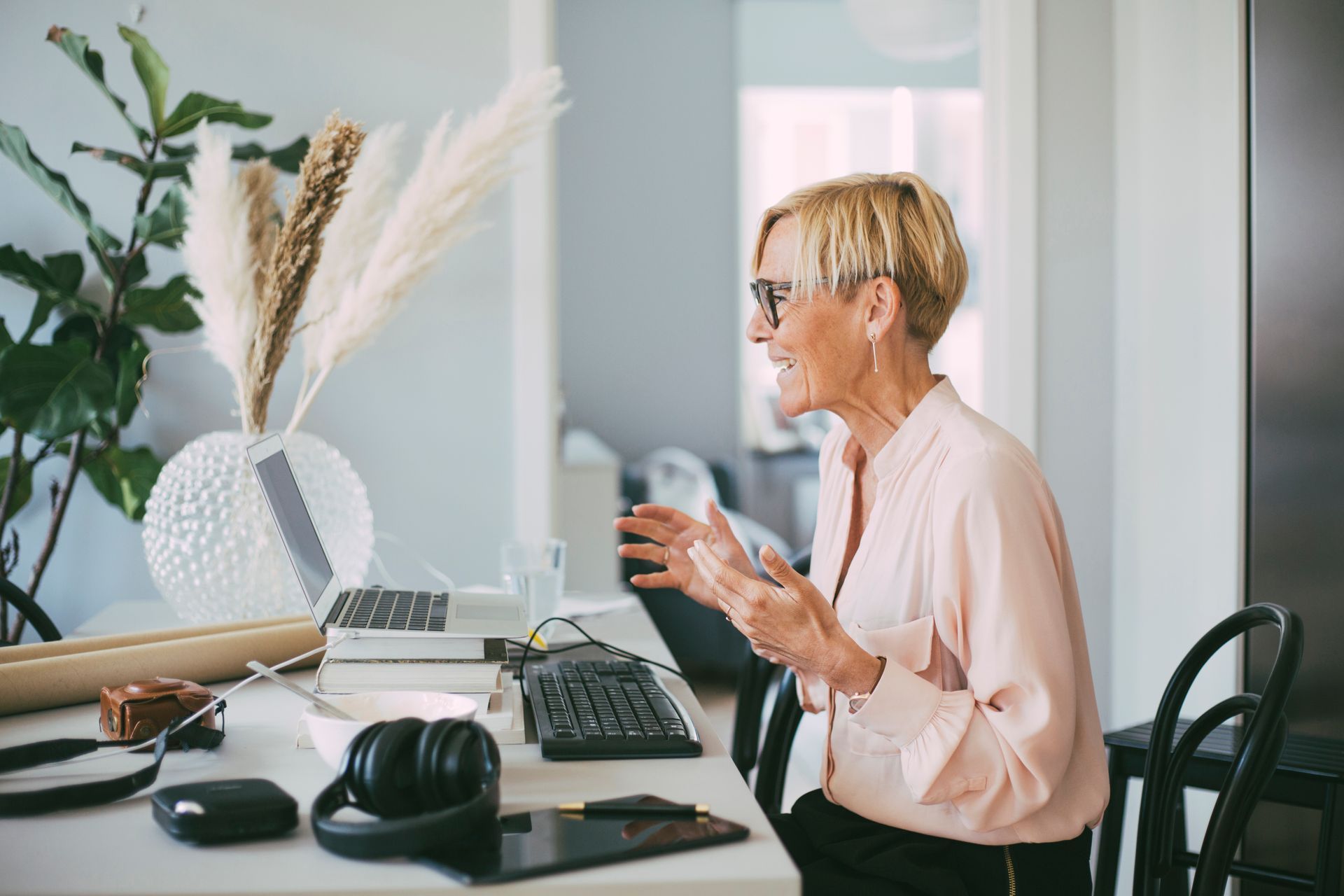 A woman is sitting at a desk with a laptop and headphones.