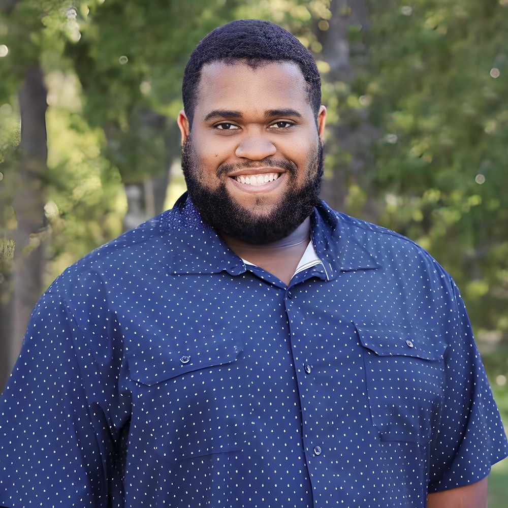 A man with a beard is wearing a blue shirt and smiling for the camera.