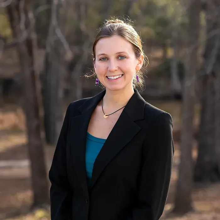 A woman in a black jacket and blue shirt is smiling for the camera.