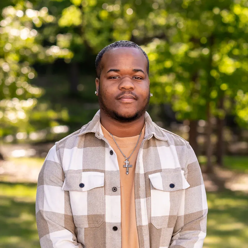 A person wearing a plaid shirt and cross necklace
