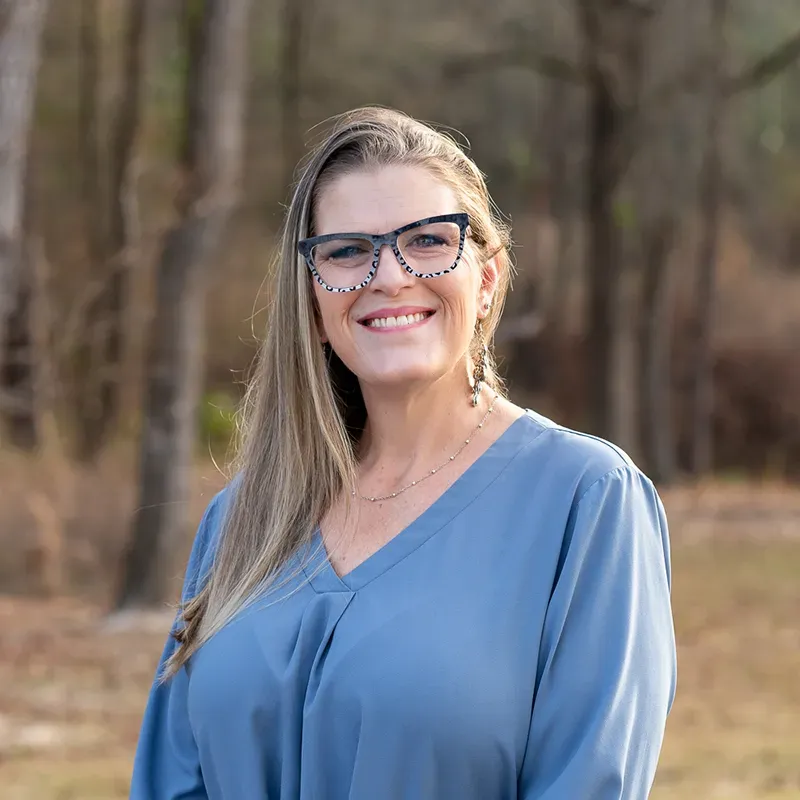 A man with a beard is leaning against a brick wall and smiling.