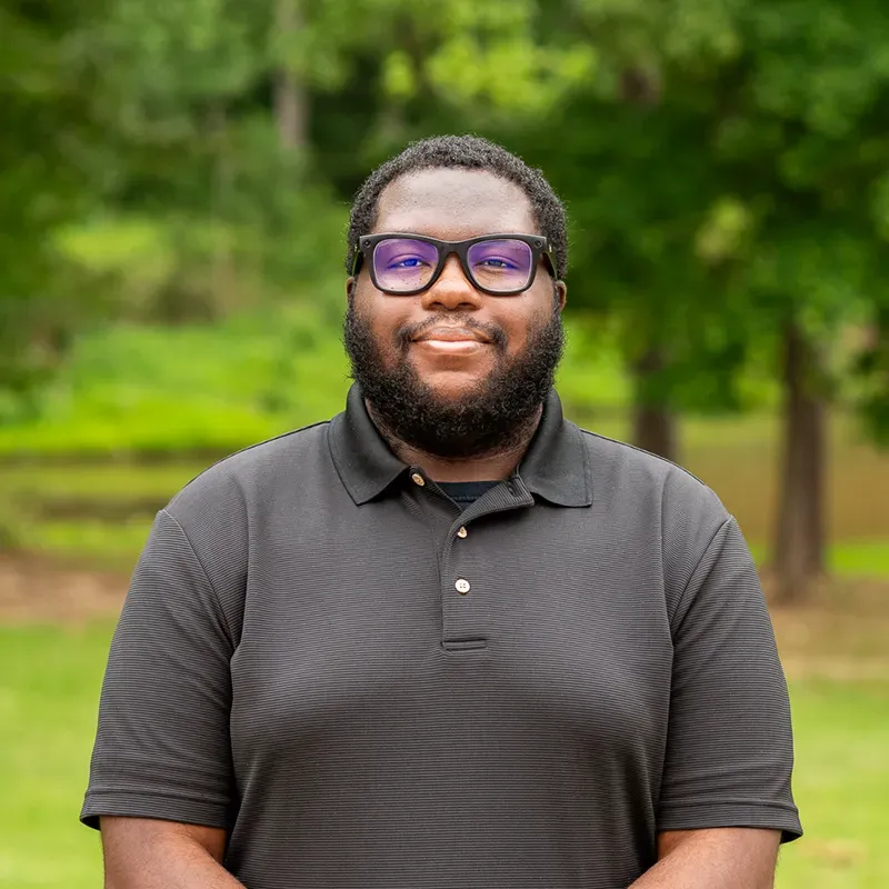 Smiling man in glasses and a dark polo shirt