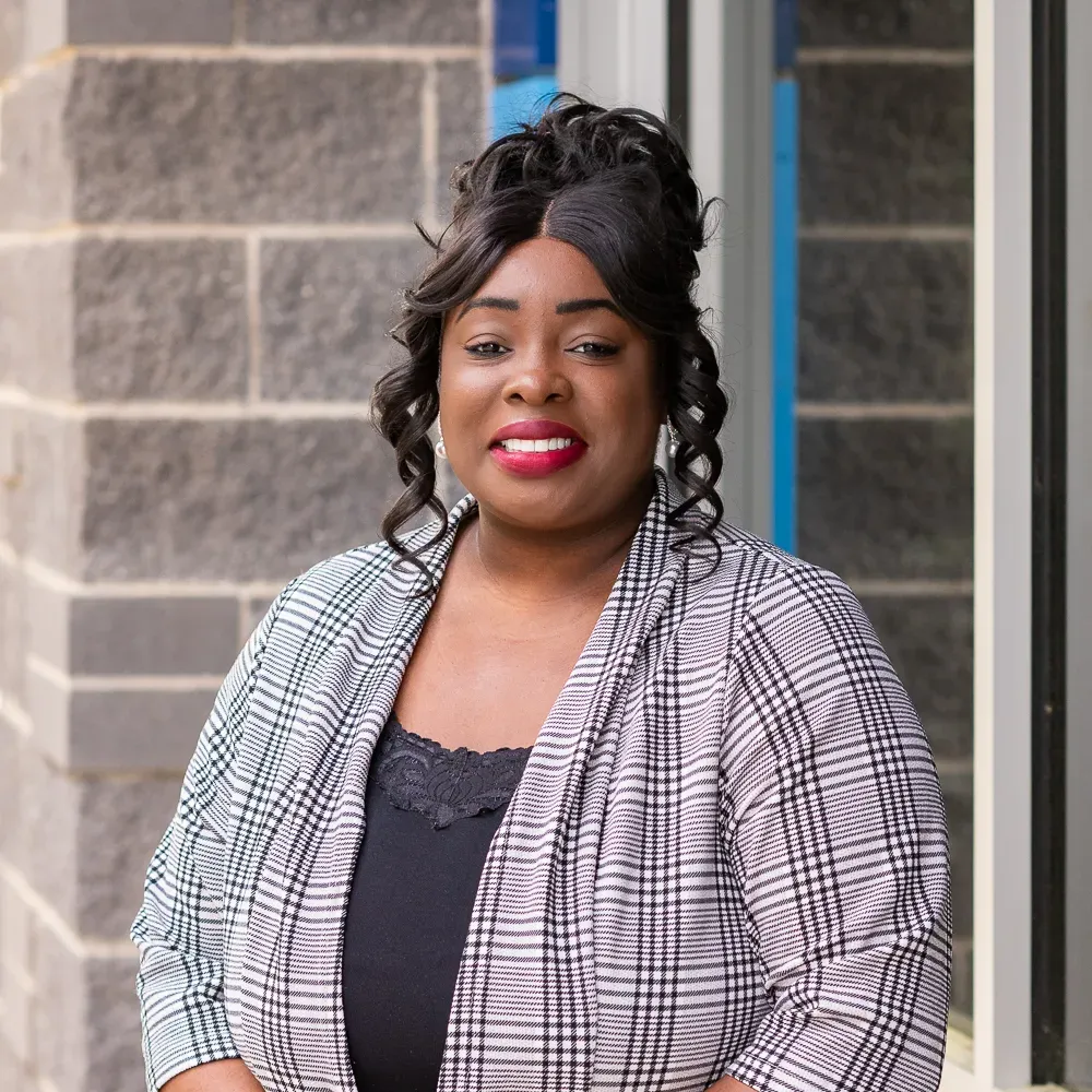 A woman with braids is wearing a red jacket and earrings.