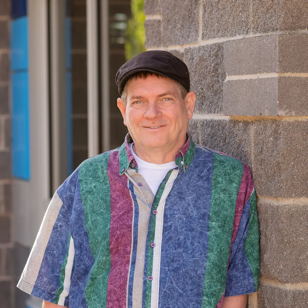 A smiling person wearing a patterned button-up shirt