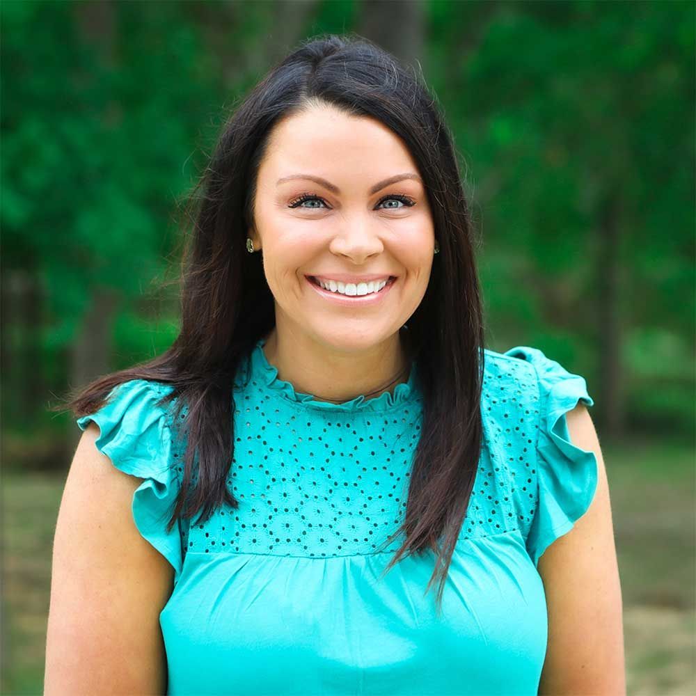 A woman in a blue shirt is smiling for the camera.