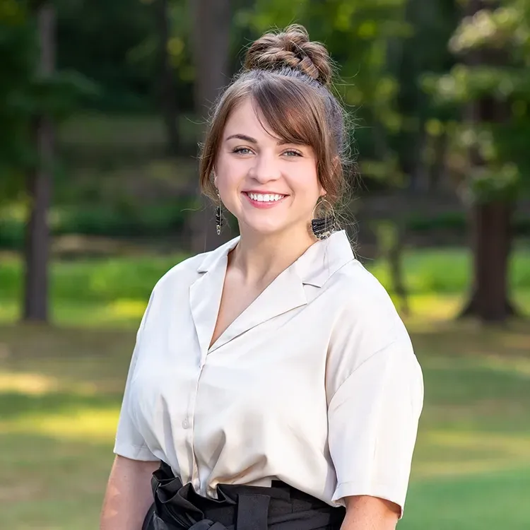 A woman in a white shirt and black skirt is smiling for the camera.