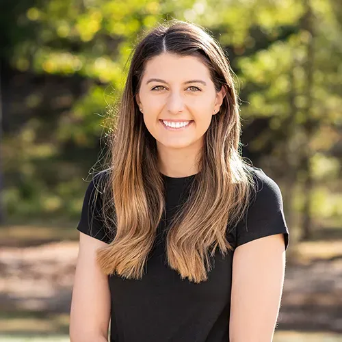 A woman in a black shirt is smiling for the camera.