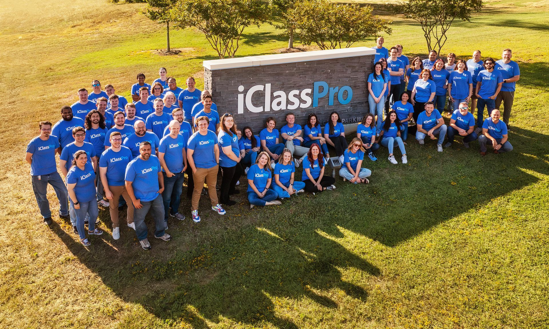 a group of employees posing in front of a sign that says iclasspro