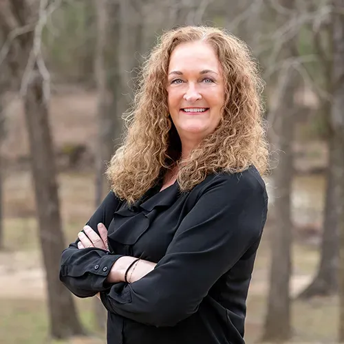 A woman in a black shirt is posing for a picture with her arms crossed.