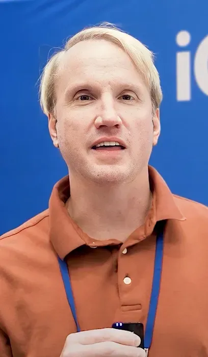 A man with a beard is wearing a lanyard around his neck.
