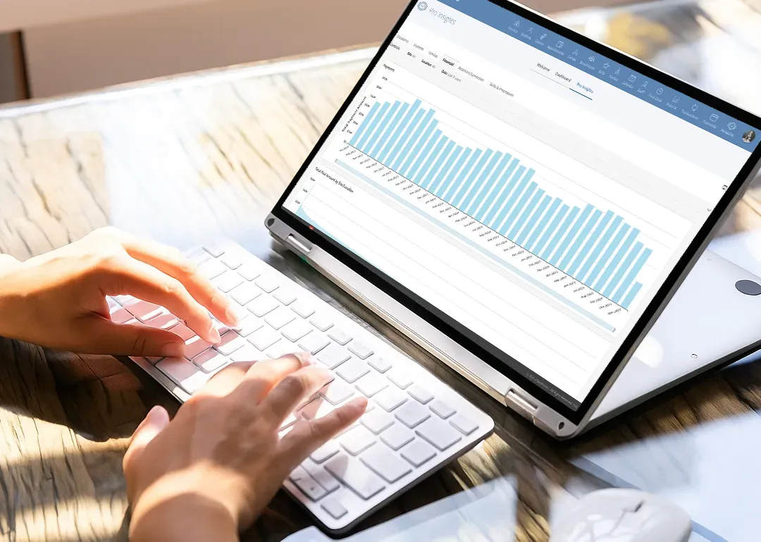 Woman using a laptop, viewing a spreadsheet and data charts on the screen.