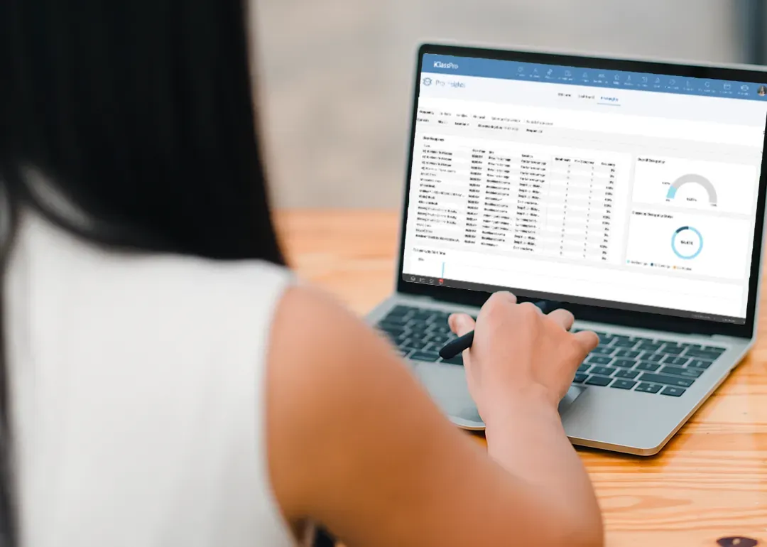 Woman using a laptop, viewing a spreadsheet and data charts on the screen.