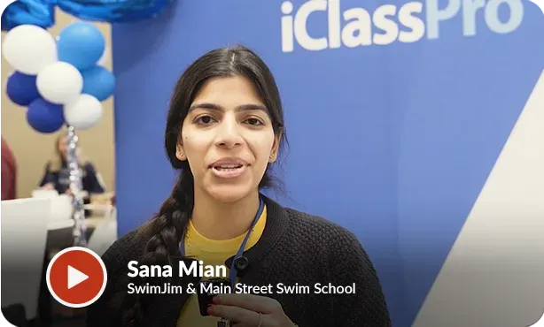 A man is standing in front of balloons and a sign that says iclass.